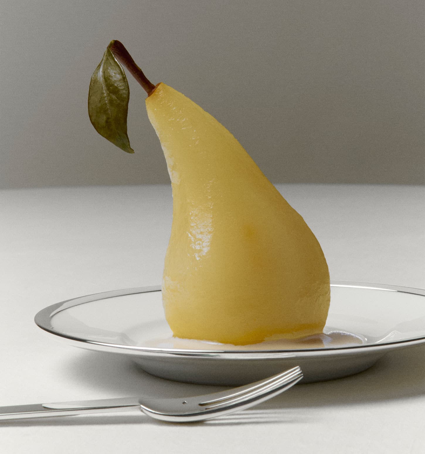 Assiettes Cercle d'Orfèvre et fourchettes Deauville dressées avec des poires pochées sur une nappe blanche