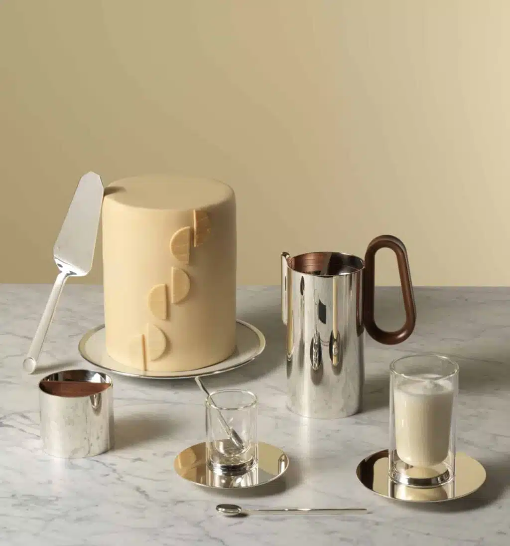 Mise en scène de la théière et du sucrier en métal argenté à côté de tasses de la collection Phi photographiés avec un gâteau sur un fond jaune clair