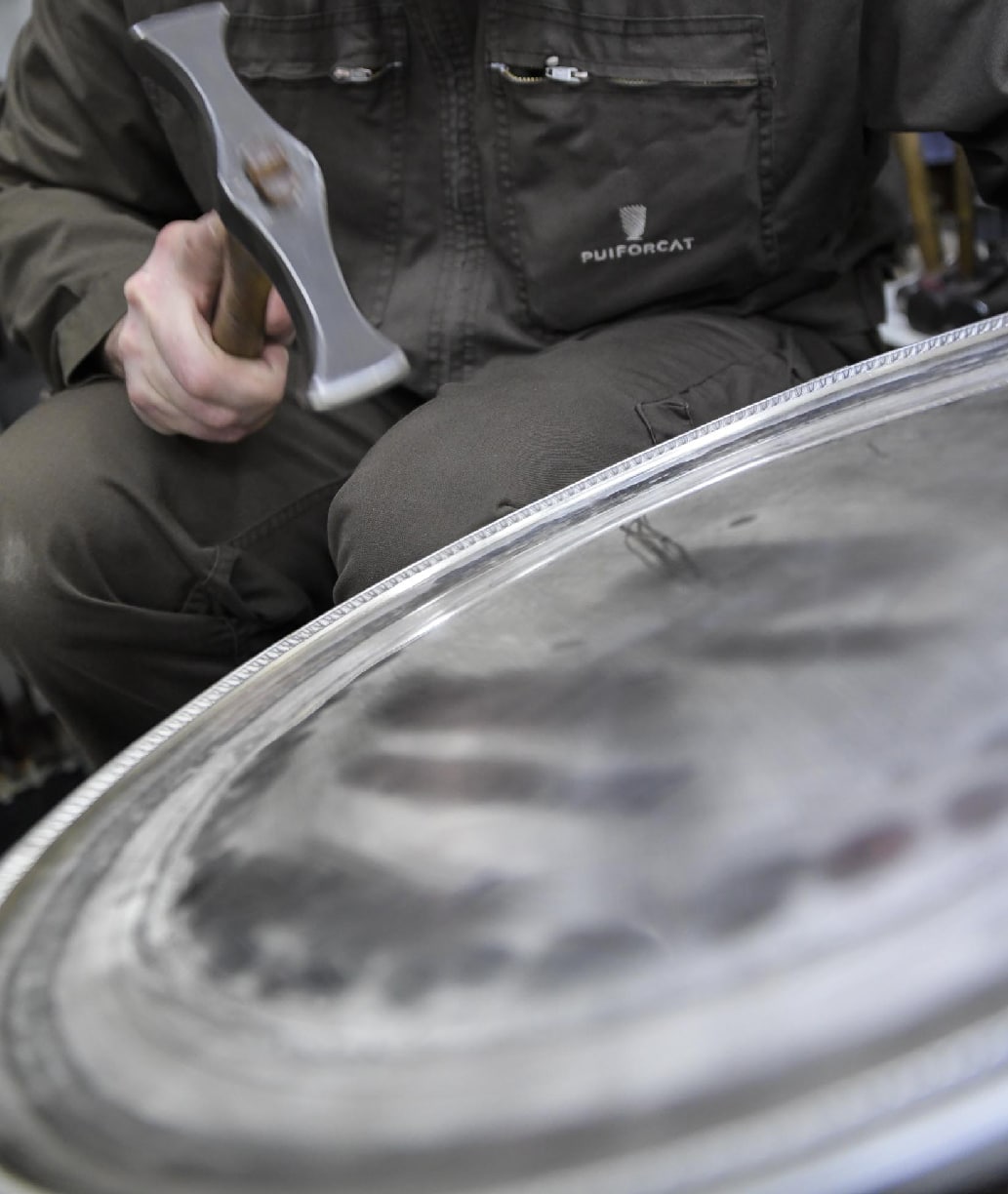 Planishing silversmith working on a sterling silver tray