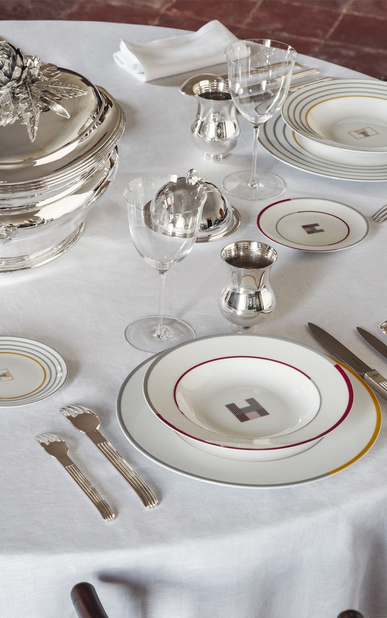 Table dressée de pièces en métal argenté et assiettes à pain, creuse et à dîner de la collection Monogrammes de Puiforcat