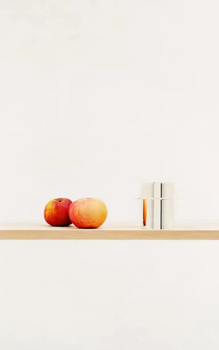 Mise en scène de pièces de la collection Dinner Service par Donald Judd de Puiforcat sur une étagère en bois, avec des légumes de toutes tailles
