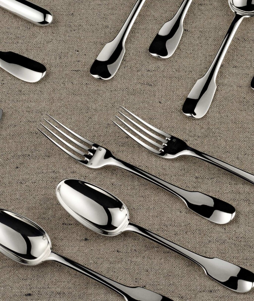 Pieces of table cutlery from Louvois collection from Puiforcat in sterling silver photographed on a beige tablecloth