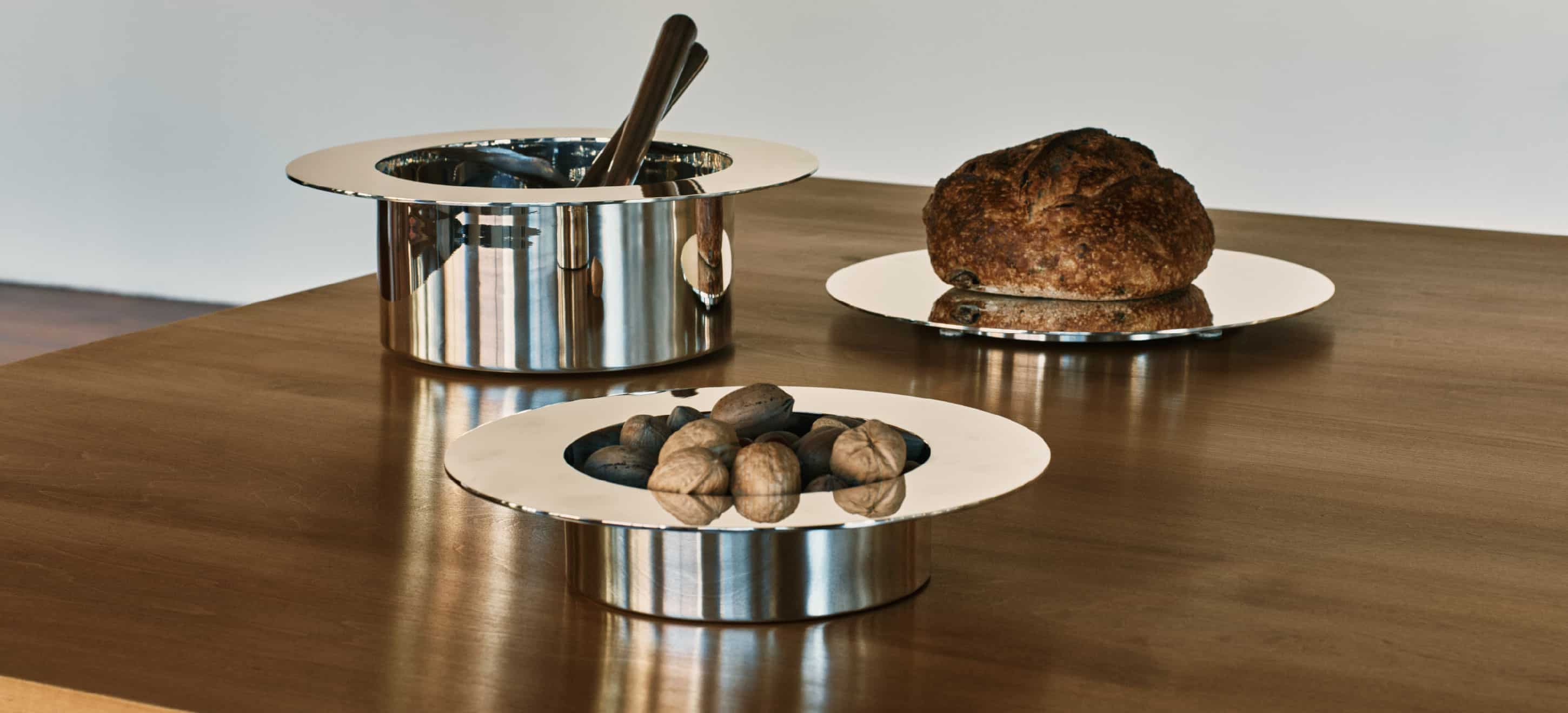 Un saladier, une assiette à diner et un plat à tarte de la collection Dinner Service par Donald Judd mis en scène sur une table en bois