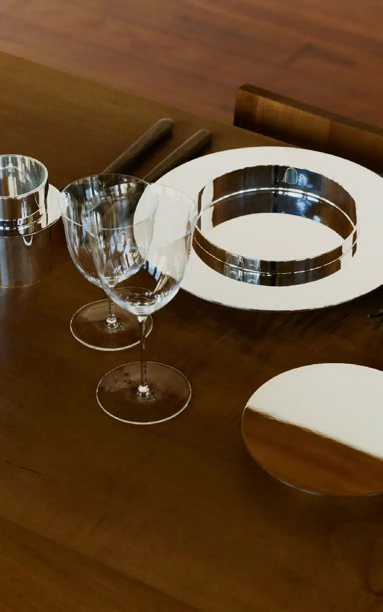A salad plate, a mug and a bread plate from Dinner Service by Donald Judd collection, photographed on a wood table with two glasses and wood cutlery at the Judd foundation in NYC