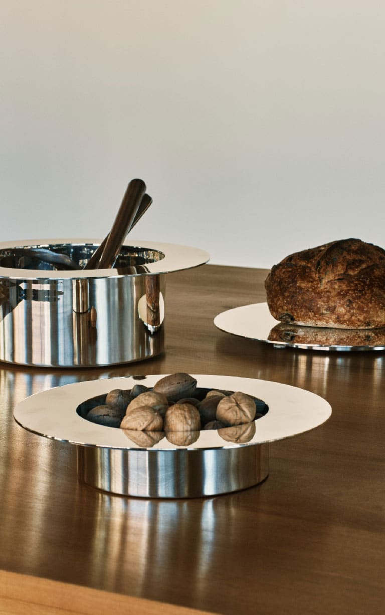 Un saladier, une assiette à diner et un plat à tarte de la collection Dinner Service par Donald Judd mis en scène sur une table en bois