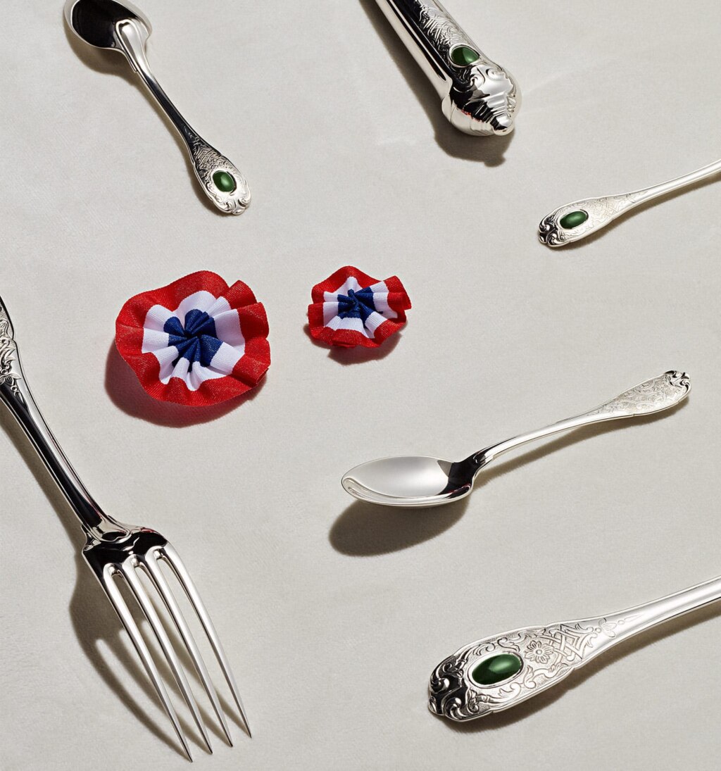 Couverts de table de la collection Elysée en argent massif et jade photographiés sur un fond blanc à côté de plusieurs cocardes tricolores en symbole de la république française