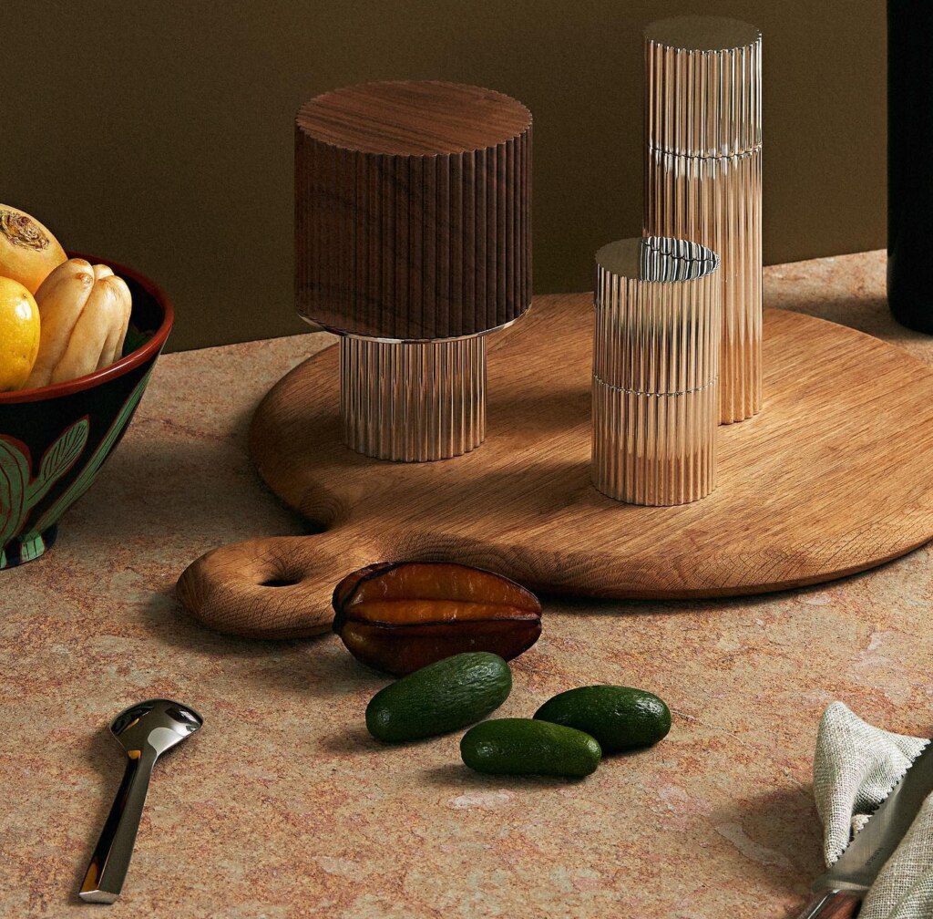 Silver plated oil dispenser, spice box, nutmeg box from Granville collection from Puiforcat photographed on a wooden tray next to some food and pieces of cutlery