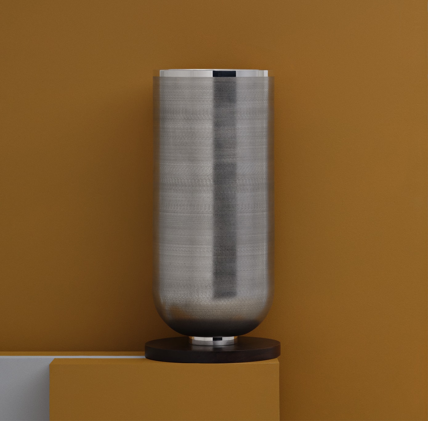 Silver plated vase from Jacaranda collection from Puiforcat on a mustard stele in front of a background in the same colour