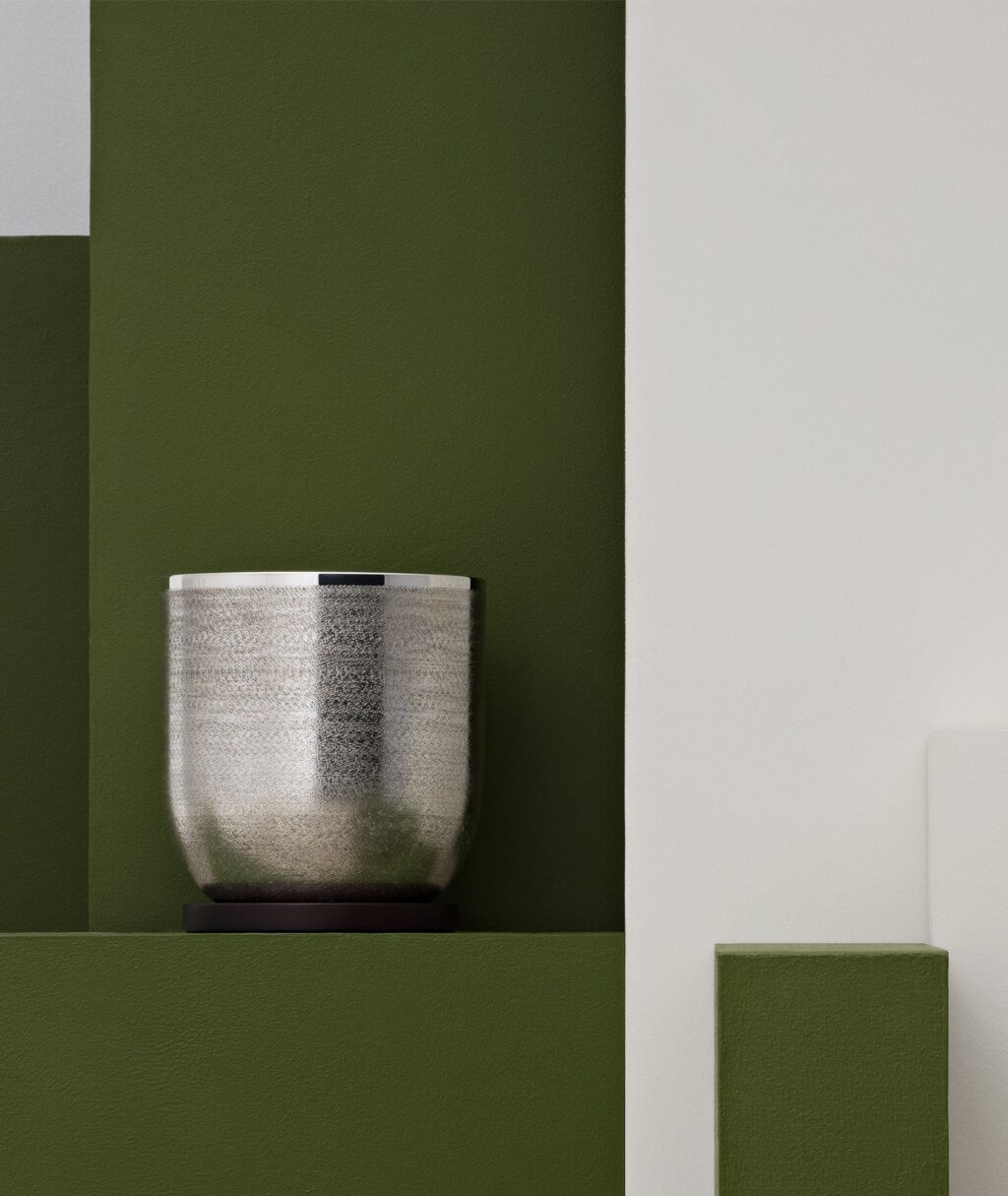 Silver plated ice bucket from Jacaranda collection from Puiforcat on a green stele in front of a background in the same colour