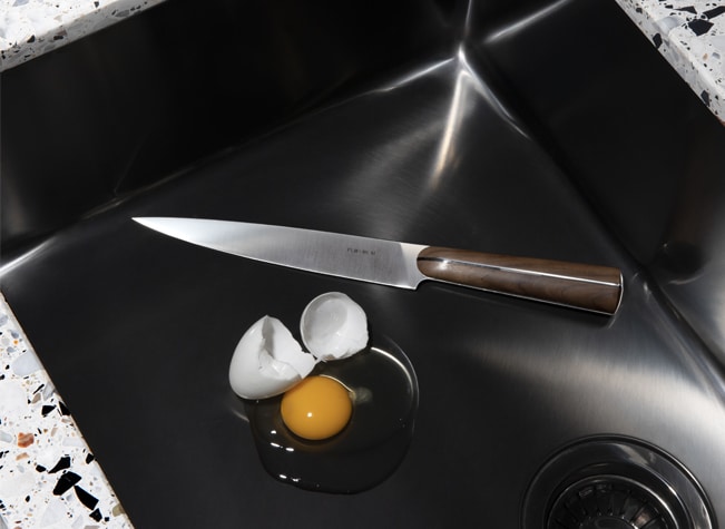 Knife from Couteaux d'orfèvre collection photographed in a sink with a broken egg