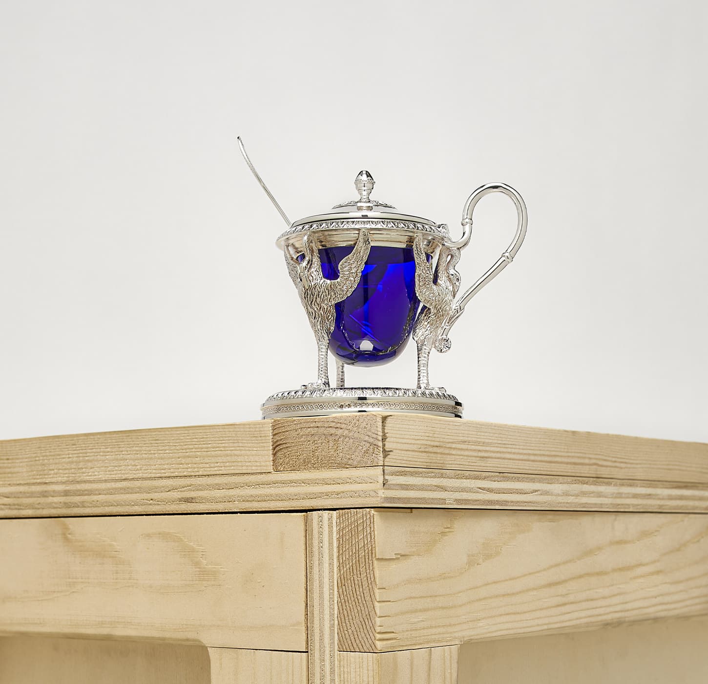Biennais mustard pot standing on a wood box, on a grey background