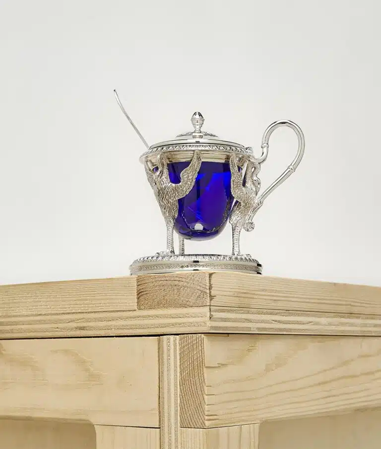 Biennais mustard pot photographed on a wood case on a grey background