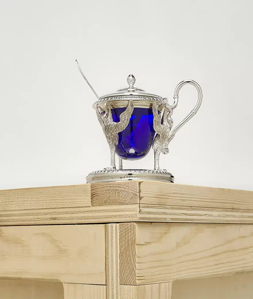 Biennais mustard pot photographed on a wood case on a grey background