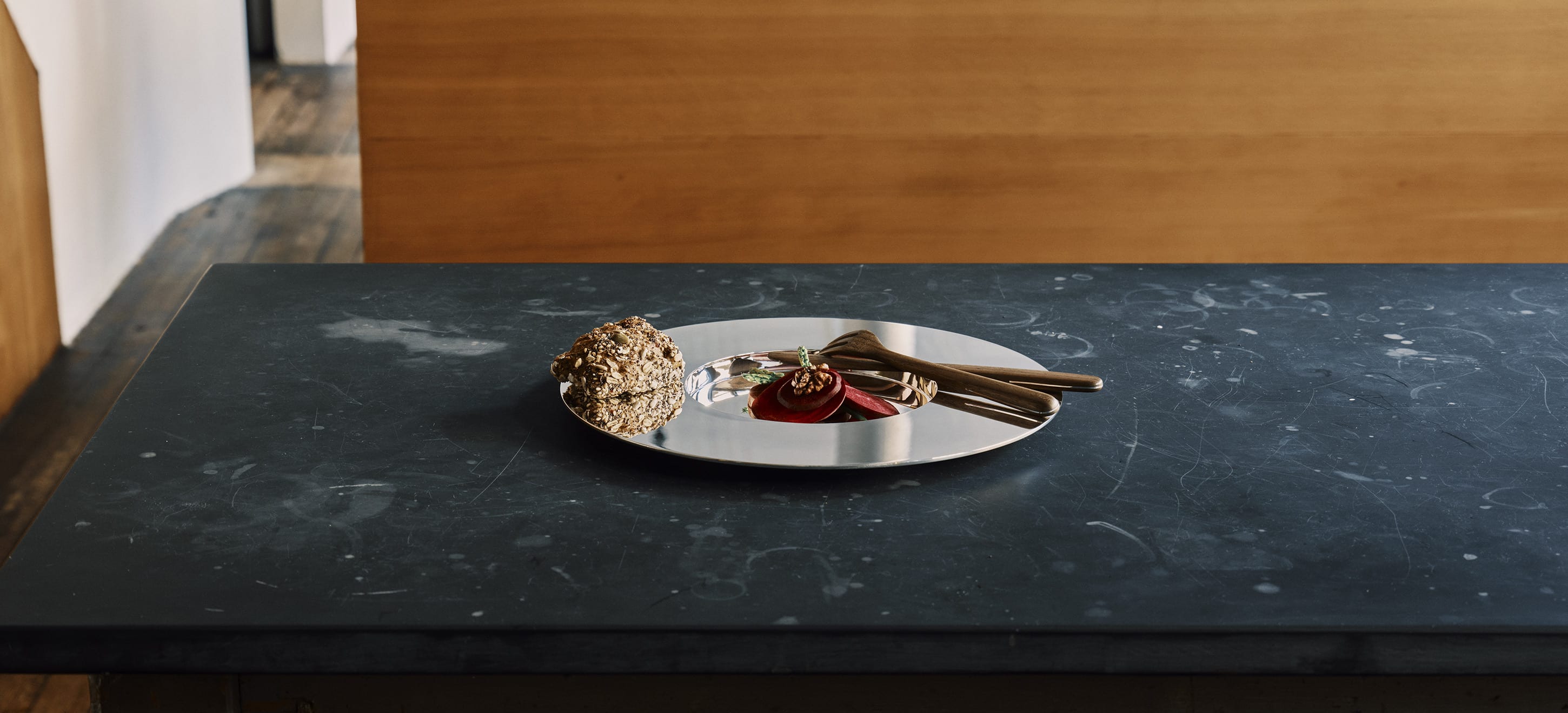 Une assiette à dîner de la collection Dinner Service par Donald Judd posés sur une table en bois