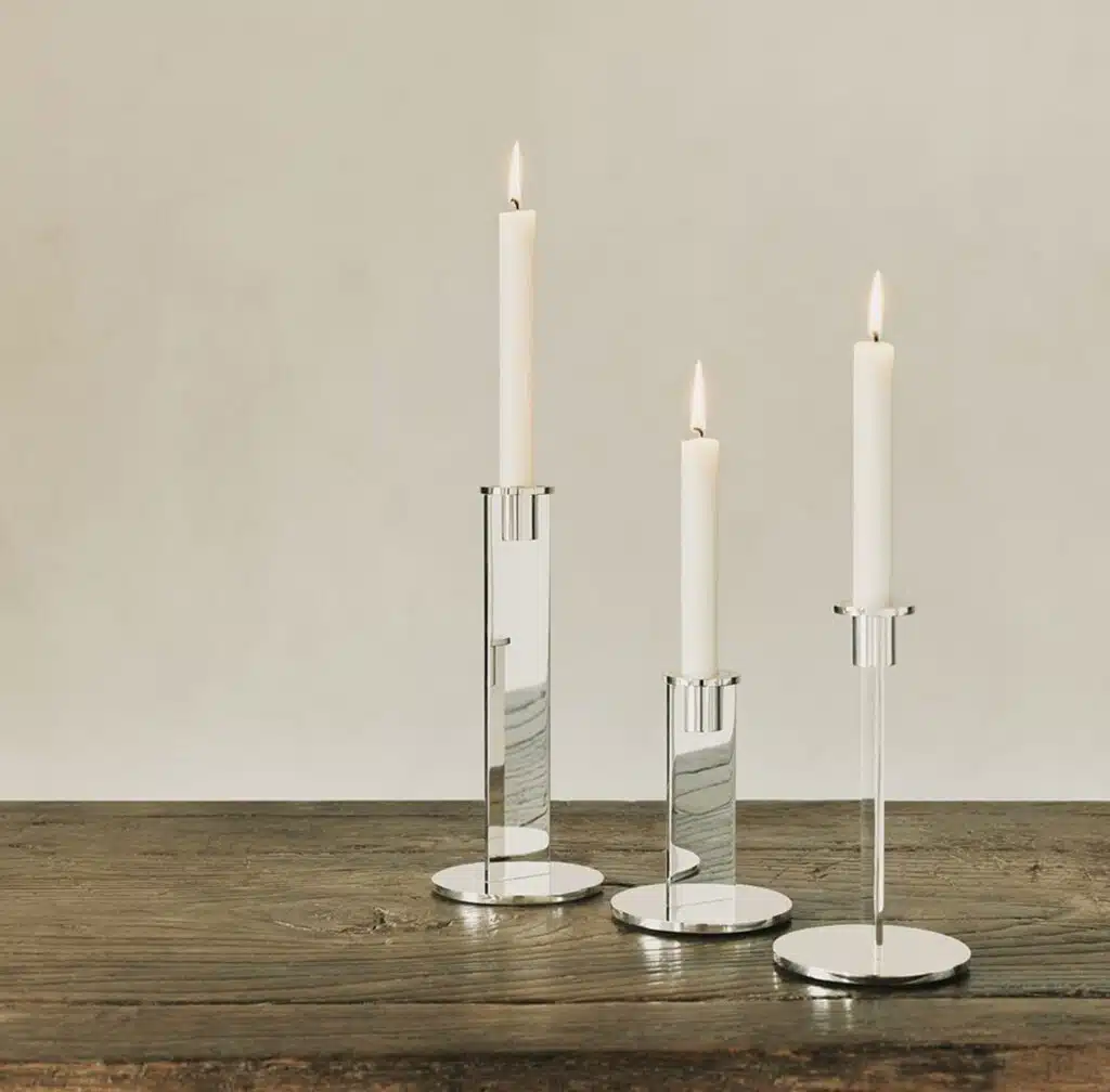 Three candle sticks from the Pilotis collection placed on a wooden table