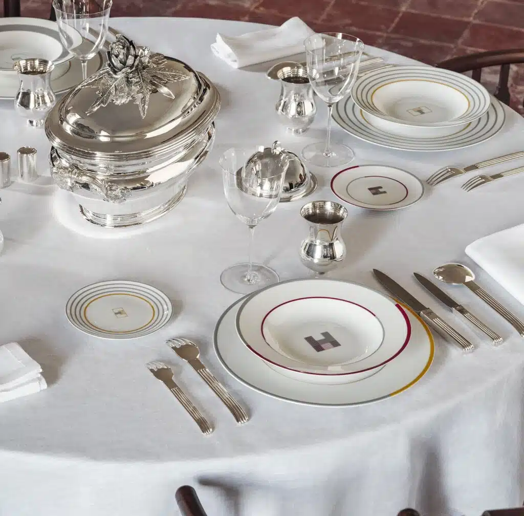 Visuel de table dressée avec le service de table Monogrammes et couverts en argent Puiforcat sur nappe blanche. 