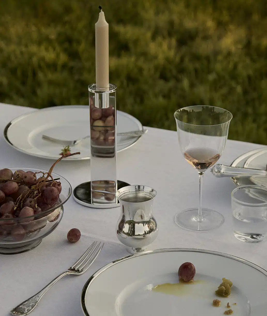 Outdoor table setting with a sterling silver tumbler and a candlestick from the Pilotis collection by Puiforcat.