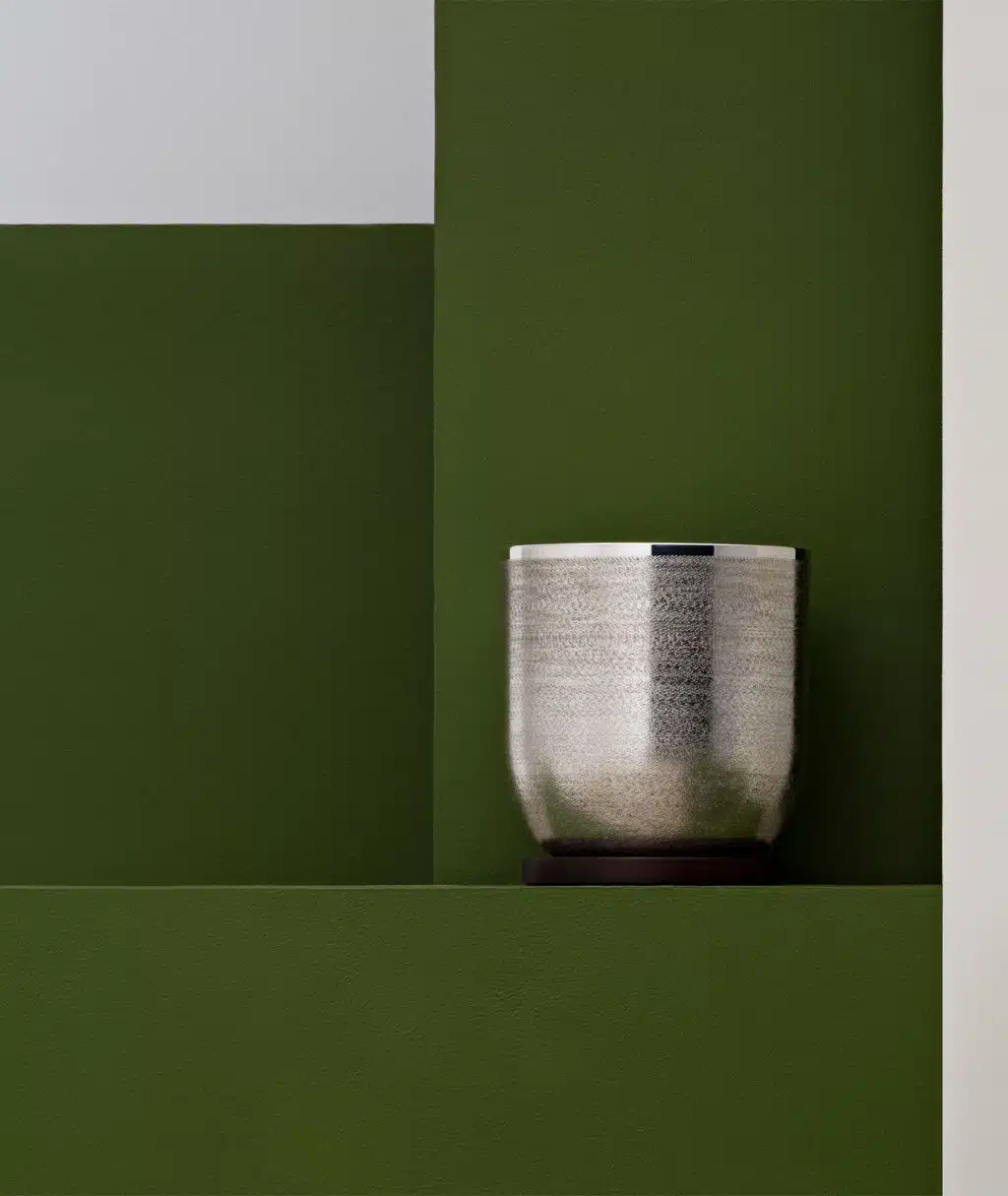 Seau à glaçons de la collection Jacaranda de Puiforcat posé sur une stèle verte, pris en photo devant un fond de la même couleur