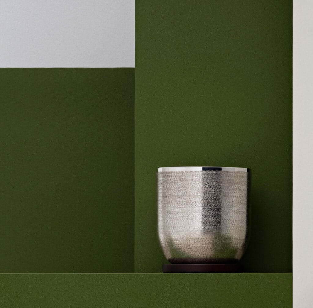 Seau à glaçons de la collection Jacaranda de Puiforcat posé sur une stèle verte, pris en photo devant un fond de la même couleur