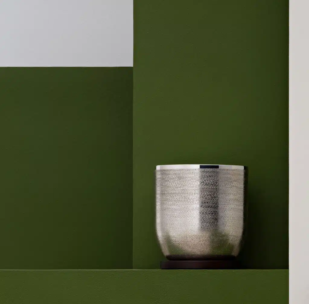 Seau à glaçons de la collection Jacaranda de Puiforcat posé sur une stèle verte, pris en photo devant un fond de la même couleur