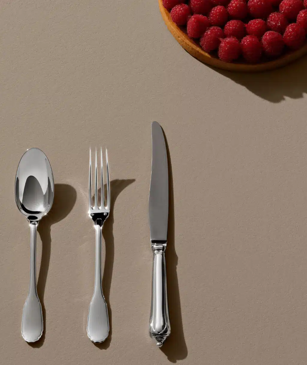 Couverts Noailles sur une table beige avec une amorçe de tarte à la framboise en haut à gauche de l'image