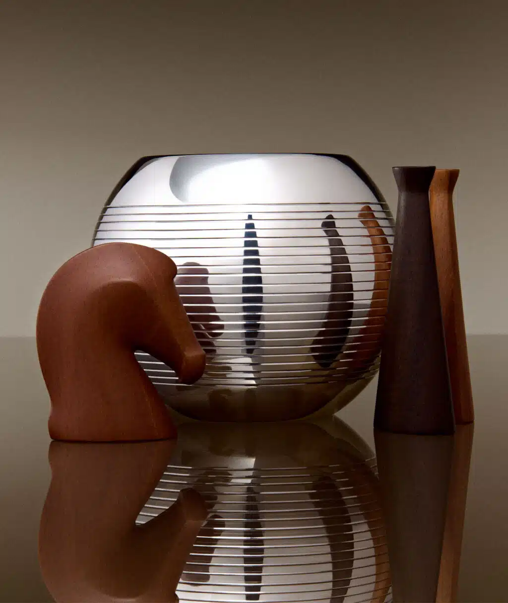 Vase Pétanque entouré de figurines en bois, le tout est posé sur une table miroir