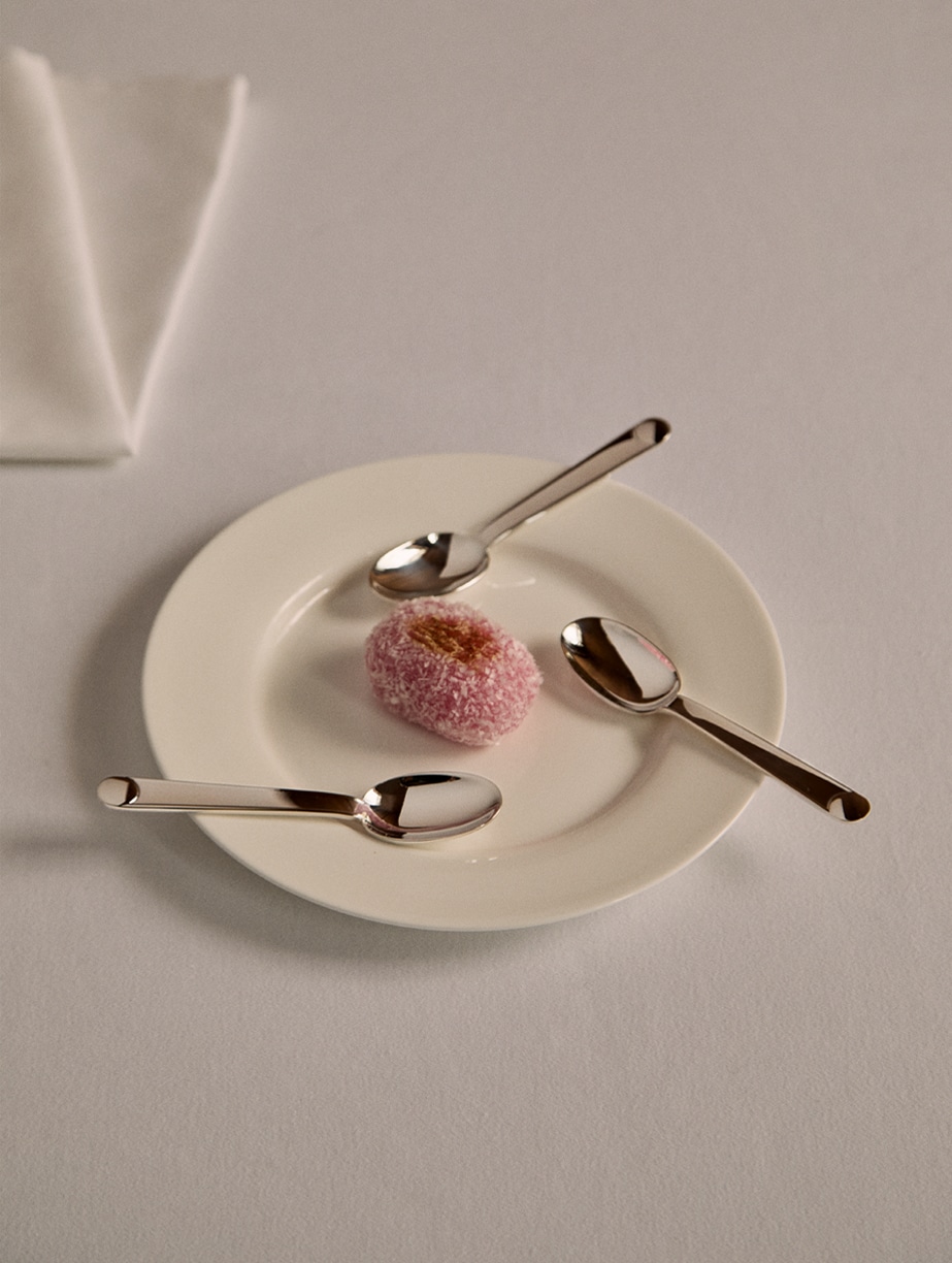 Cuillers à thé & café de la collection Normandie disposés autour d'un mochi sur une assiette blanche sur une nappe blanche