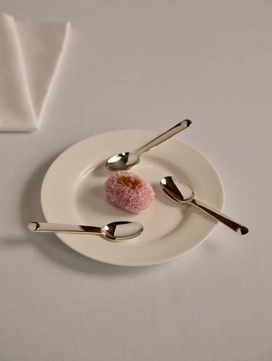 Cuillers à thé & café de la collection Normandie disposés autour d'un mochi sur une assiette blanche sur une nappe blanche